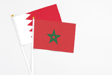 Morocco and Bahrain stick flags on white background. High quality fabric, miniature national flag. Peaceful global concept.White floor for copy space.