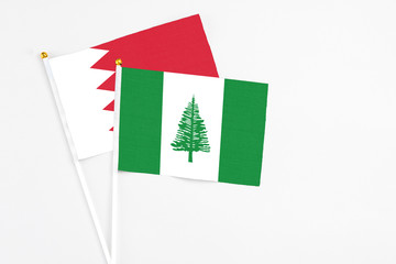 Norfolk Island and Bahrain stick flags on white background. High quality fabric, miniature national flag. Peaceful global concept.White floor for copy space.