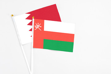 Oman and Bahrain stick flags on white background. High quality fabric, miniature national flag. Peaceful global concept.White floor for copy space.