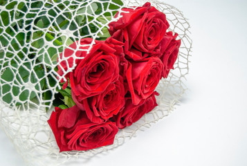 A bouquet of red roses lies on a white table.