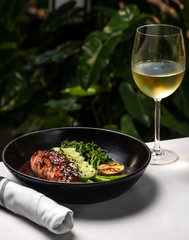 Haute cuisine - grilled salmon with asparagus and cucumbers on a side in a dark bowl outside...