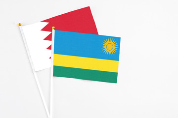 Rwanda and Bahrain stick flags on white background. High quality fabric, miniature national flag. Peaceful global concept.White floor for copy space.