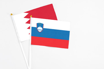 Slovenia and Bahrain stick flags on white background. High quality fabric, miniature national flag. Peaceful global concept.White floor for copy space.