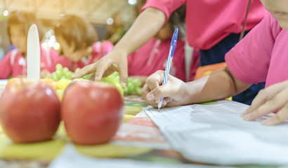 Primary school girls learn and take notes about different types of fruits at school.