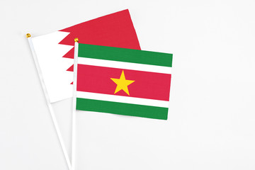Suriname and Bahrain stick flags on white background. High quality fabric, miniature national flag. Peaceful global concept.White floor for copy space.