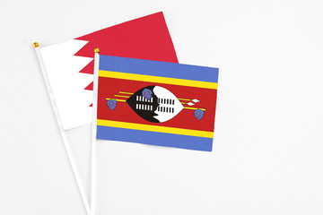 Swaziland and Bahrain stick flags on white background. High quality fabric, miniature national flag. Peaceful global concept.White floor for copy space.