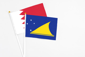 Tokelau and Bahrain stick flags on white background. High quality fabric, miniature national flag. Peaceful global concept.White floor for copy space.