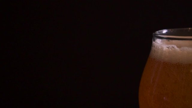 Fancy pint of craft beer sitting on a table with black background, slow motion truck right