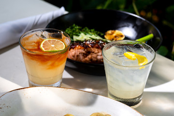 Two fresh alcohol cocktail or lemonade beverage outside of restaurant in a summer day