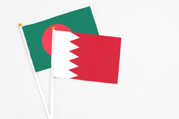 Bahrain and Bangladesh stick flags on white background. High quality fabric, miniature national flag. Peaceful global concept.White floor for copy space.