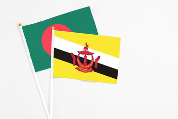 Brunei and Bangladesh stick flags on white background. High quality fabric, miniature national flag. Peaceful global concept.White floor for copy space.