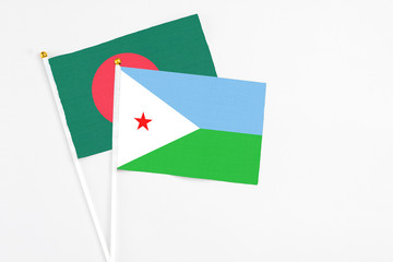 Djibouti and Bangladesh stick flags on white background. High quality fabric, miniature national flag. Peaceful global concept.White floor for copy space.