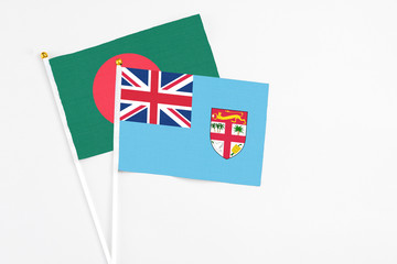 Fiji and Bangladesh stick flags on white background. High quality fabric, miniature national flag. Peaceful global concept.White floor for copy space.