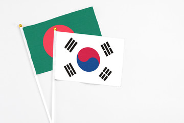 South Korea and Bangladesh stick flags on white background. High quality fabric, miniature national flag. Peaceful global concept.White floor for copy space.