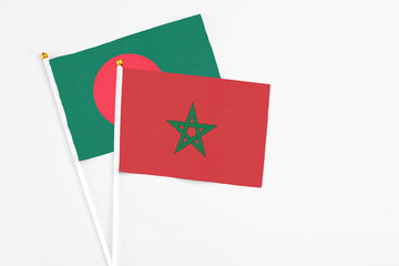 Morocco and Bangladesh stick flags on white background. High quality fabric, miniature national flag. Peaceful global concept.White floor for copy space.