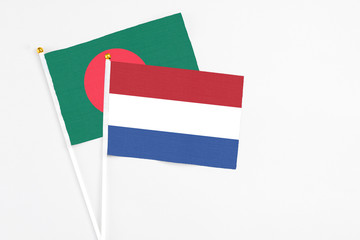 Netherlands and Bangladesh stick flags on white background. High quality fabric, miniature national flag. Peaceful global concept.White floor for copy space.