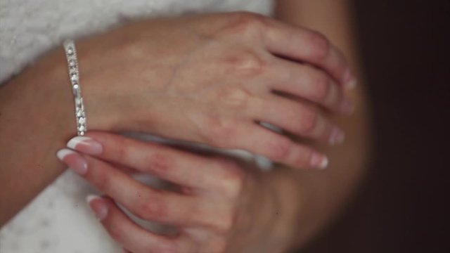 the bride tries on jewelry. The model shows the bracelet. French manicure with rhinestones