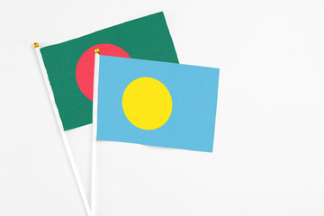 Palau and Bangladesh stick flags on white background. High quality fabric, miniature national flag. Peaceful global concept.White floor for copy space.