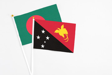 Papua New Guinea and Bangladesh stick flags on white background. High quality fabric, miniature national flag. Peaceful global concept.White floor for copy space.