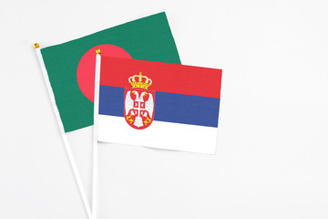 Serbia and Bangladesh stick flags on white background. High quality fabric, miniature national flag. Peaceful global concept.White floor for copy space.