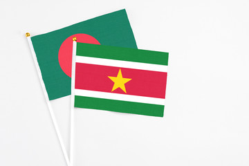 Suriname and Bangladesh stick flags on white background. High quality fabric, miniature national flag. Peaceful global concept.White floor for copy space.