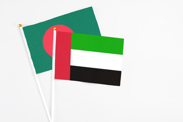 United Arab Emirates and Bangladesh stick flags on white background. High quality fabric, miniature national flag. Peaceful global concept.White floor for copy space.