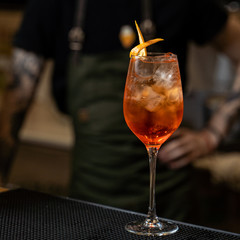 Bartender is making aperol spritz on a bar counter in a restaurant