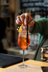 Woman is drinking Aperol Spritz in a soft sunny daylight