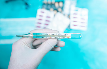 Medical mercury thermometer on the background of pills.