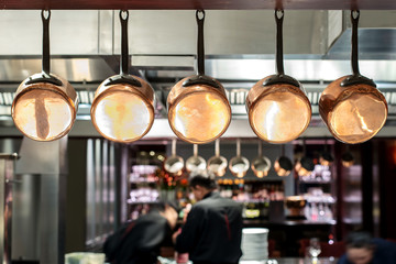 saucepans hanging from a rack in busy kitchen