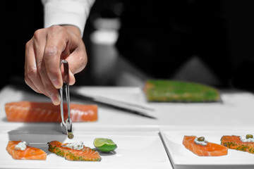 Obraz na płótnie Canvas Professional chef decorating caper on sliced salmon