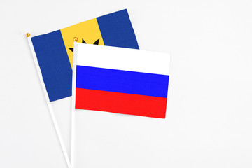 Russia and Barbados stick flags on white background. High quality fabric, miniature national flag. Peaceful global concept.White floor for copy space.
