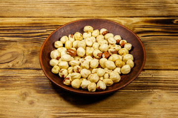 Peeled hazelnuts in ceramic plate on wooden table