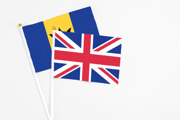 Fototapeta premium United Kingdom and Barbados stick flags on white background. High quality fabric, miniature national flag. Peaceful global concept.White floor for copy space.