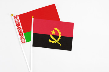 Angola and Belarus stick flags on white background. High quality fabric, miniature national flag. Peaceful global concept.White floor for copy space.