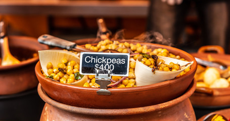 Cooked chickpeas are for sale at $4 per serve inside a warm clay pot at a street vendors stall