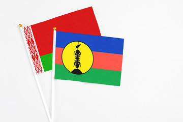 New Caledonia and Belarus stick flags on white background. High quality fabric, miniature national flag. Peaceful global concept.White floor for copy space.