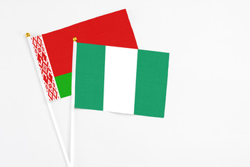 Nigeria and Belarus stick flags on white background. High quality fabric, miniature national flag. Peaceful global concept.White floor for copy space.