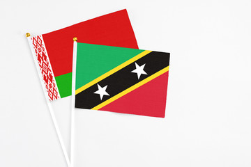 Saint Kitts And Nevis and Belarus stick flags on white background. High quality fabric, miniature national flag. Peaceful global concept.White floor for copy space.