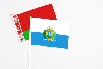 San Marino and Belarus stick flags on white background. High quality fabric, miniature national flag. Peaceful global concept.White floor for copy space.