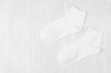 Pair blank white medium socks flat lay on white wood board, side view - mock up for design, print, presentation, advertising, top view, copy space.