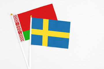 Sweden and Belarus stick flags on white background. High quality fabric, miniature national flag. Peaceful global concept.White floor for copy space.