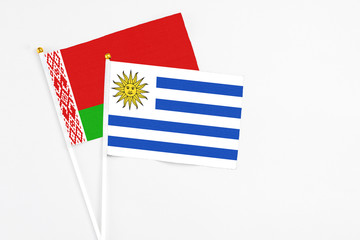 Uruguay and Belarus stick flags on white background. High quality fabric, miniature national flag. Peaceful global concept.White floor for copy space.
