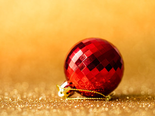 Red christmas ball on gold glitter background.