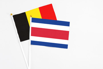Costa Rica and Belgium stick flags on white background. High quality fabric, miniature national flag. Peaceful global concept.White floor for copy space.