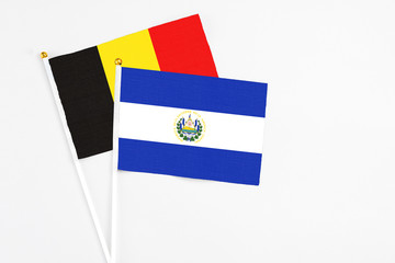 El Salvador and Belgium stick flags on white background. High quality fabric, miniature national flag. Peaceful global concept.White floor for copy space.