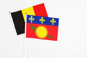 Guadeloupe and Belgium stick flags on white background. High quality fabric, miniature national flag. Peaceful global concept.White floor for copy space.