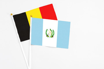 Guatemala and Belgium stick flags on white background. High quality fabric, miniature national flag. Peaceful global concept.White floor for copy space.