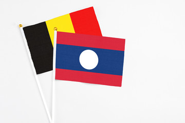 Laos and Belgium stick flags on white background. High quality fabric, miniature national flag. Peaceful global concept.White floor for copy space.