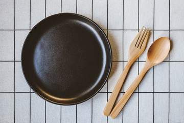 Empty black plate, Top view of dinner set with on food, Wooden spoon and fork on table pattern desk, with blank copy space